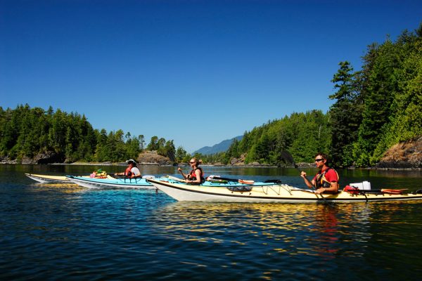 A group of kayakers paddling through a channel on the west coast