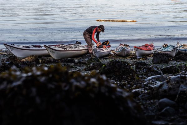 A guide packing their kayak on a rocky shoreline in Coastal BC