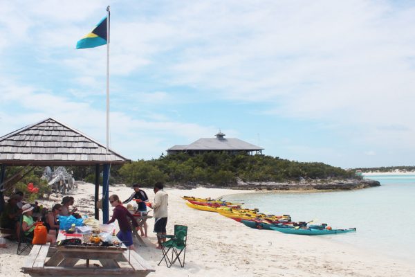 A group of people eating lunch at a picnic table on a beach in the Bahamas