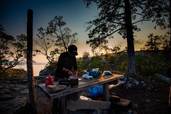 A guide cooking dinner on a table in Desolation Sound